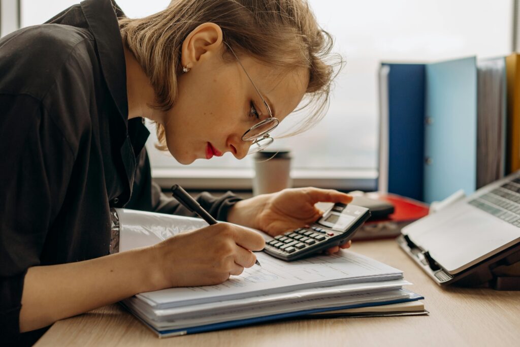 Woman holding a calculator and writing in a notebook